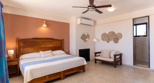 a bedroom with a bed and a fan and a chair at Hotel El Mirador in Puerto Escondido