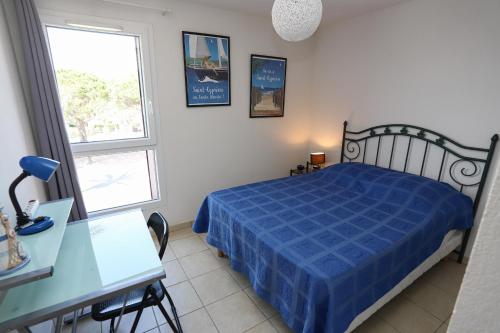 - une chambre avec un lit bleu, un bureau et une fenêtre dans l'établissement St Cyprien coup de coeur vue sur la mer, à Saint-Cyprien
