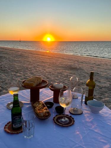 a table with wine glasses and food on the beach at ENTREMER in Belo