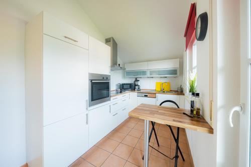 a kitchen with white cabinets and a wooden table at Ferienwohnung Bergblick in Samerberg