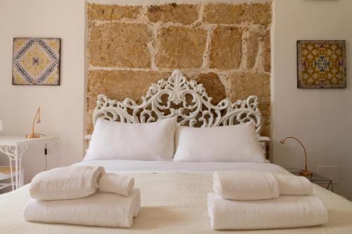 een slaapkamer met een wit bed en een stenen muur bij Intalloi in Noto