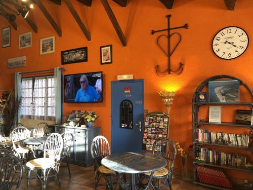 a restaurant with tables and chairs and a clock on the wall at Hotel Des 4 Vents "Esprit Camargue" Parking Privé securisé in Aigues-Mortes