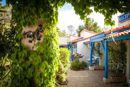 a wall covered in green ivy next to a building at Hotel Des 4 Vents "Esprit Camargue" Parking Privé securisé in Aigues-Mortes
