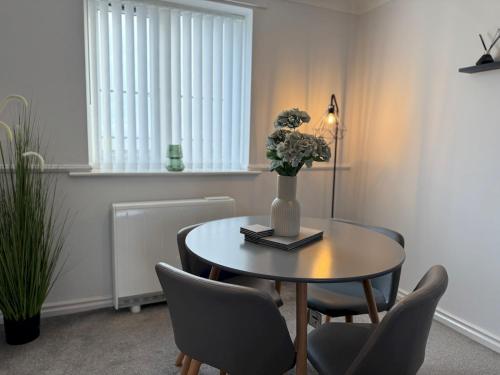 a dining room with a table with chairs and a vase with flowers at Your Home on the Marina Pass The Keys in Hartlepool