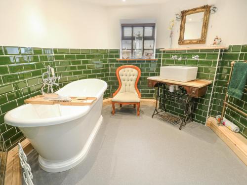 a green tiled bathroom with a tub and a desk at Old Tollgate in Holyhead