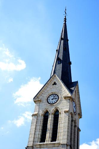 a clock tower with a steeple with a clock on it at Logis Hôtel Restaurant Barrey in Orchamps-Vennes