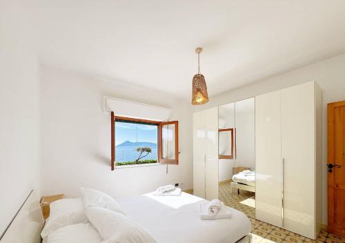 Un dormitorio blanco con una cama y una ventana. en Solemar Sicilia - Ville Paradiso, en Santa Flavia