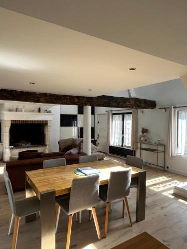 un salon avec une table et des chaises en bois dans l'établissement Maison avec cheminée ancienne - Proche Cabourg, à Dives-sur-Mer