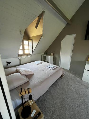 une chambre mansardée avec un lit et une fenêtre dans l'établissement Maison avec cheminée ancienne - Proche Cabourg, à Dives-sur-Mer