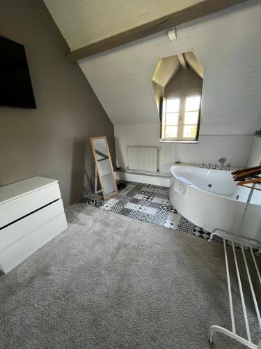 La salle de bains est pourvue d'une baignoire blanche et d'un miroir. dans l'établissement Maison avec cheminée ancienne - Proche Cabourg, à Dives-sur-Mer