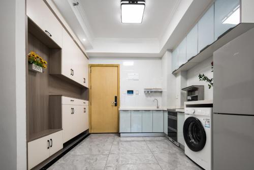 a large white kitchen with a washer and dryer at Ode to Joy Hotel Apartment East Railway Station Guanghuan Shopping Park Branch in Chengdu