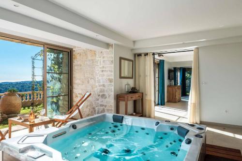 - une grande baignoire bleue dans une chambre dotée d'une grande fenêtre dans l'établissement Appartement de Charme avec jacuzzi et sauna – Une Expérience Authentique et Intemporelle, à La Colle-sur-Loup