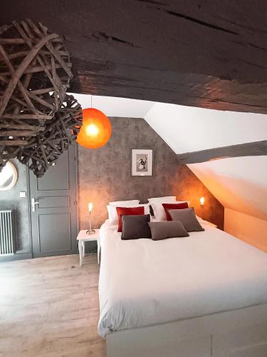 une chambre avec un grand lit blanc avec des oreillers rouges dans l'établissement LE JARDIN DE LA PICHONNERIE Chambres d'hôtes, à Thésée