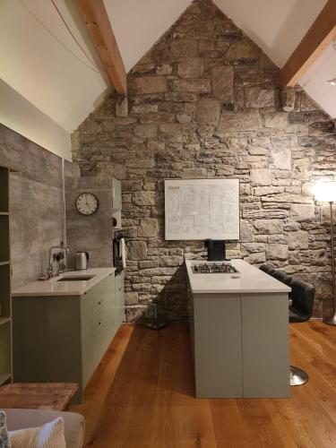 a kitchen with a stone wall with a sink and a stove at The Burren, Cozy Cottage, County Clare in Carran