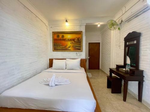 a bedroom with a bed and a desk and a mirror at Rumah Rini by Rumah Weda in Ubud