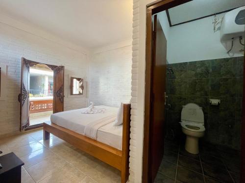 a bathroom with a bed and a toilet in a room at Rumah Rini by Rumah Weda in Ubud