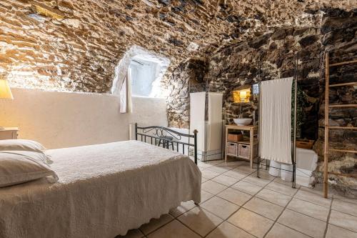 Un dormitorio con una cama y una pared de piedra. en U Fragnu - A 10min de LIle-Rousse, en Santa-Reparata-di-Balagna