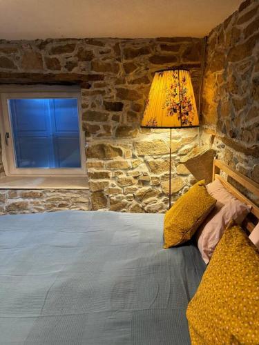 a bedroom with a bed with a stone wall at Ta Petrina Cottage in Selishte