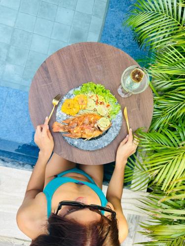 a woman is holding a table with a plate of food at Mantra Hotel Boutique in Santa Marta