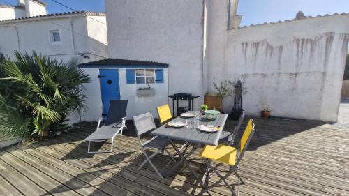 une table et des chaises sur une terrasse avec une porte bleue dans l'établissement Saint Palais sur Mer - PROXIMITÉ LAC pour cette petite MAISON MITOYENNE - WIFI, à La Palud