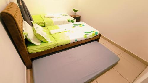 a bed with green sheets and a bench in a room at Kulai d'putra suites beside ioiMall near Airport and JPO in Kulai