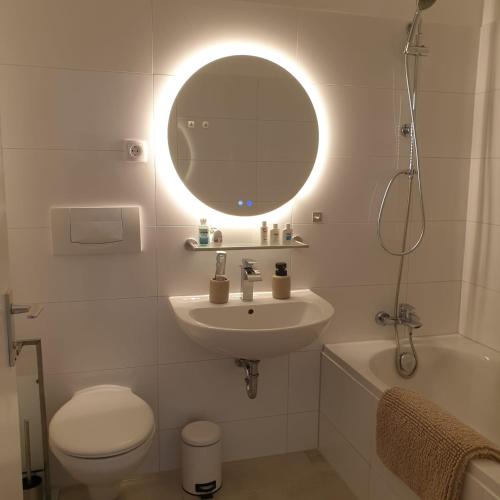 ein Badezimmer mit Waschbecken, Toilette und Spiegel in der Unterkunft BonnJour - 7 Lounge Apartment in Bonn