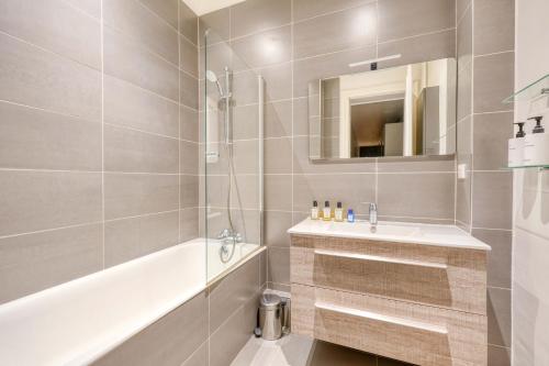 La salle de bains est pourvue d'une baignoire, d'un lavabo et d'un miroir. dans l'établissement Appartement Bugeaud Luxury, à Paris