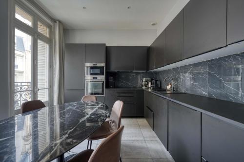une cuisine avec un comptoir noir et une table dans l'établissement Appartement Bugeaud Luxury, à Paris