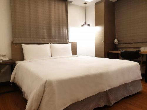 a bedroom with a large white bed with a window at CHECK inn Express Taipei Station in Taipei
