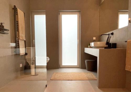 a bathroom with a sink and a toilet and a window at Pomar da Choca Country House in Alenquer