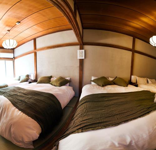 two beds in a room with wooden ceilings at MSTAY東池袋one in Tokyo