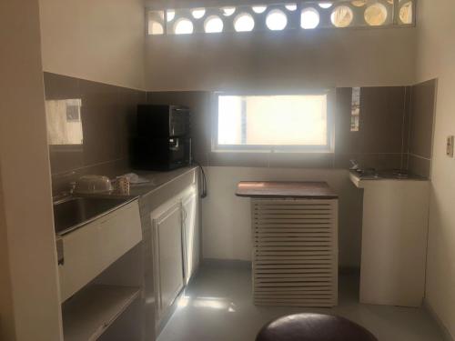 mała kuchnia ze zlewem i kuchenką mikrofalową w obiekcie studio sacre coeur w mieście Dakar