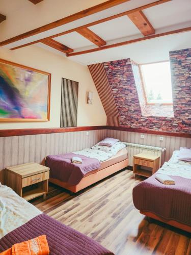 a room with two beds and a brick wall at Pensjonat Li-Mar in Pisz