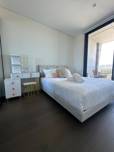 a white bedroom with a bed and a desk at Golden Sunset Retreat In Olympic Park in Sydney