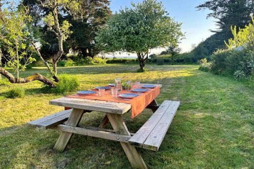une table de pique-nique en bois avec des assiettes et des verres dessus dans l'établissement La Paisible - 50m mer - Jardin, à La Bernerie-en-Retz