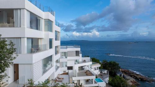 a white building overlooking the ocean with a body of water at Shenzhen GuanHu Secret Wild Reef Seaview Hotel in Shenzhen