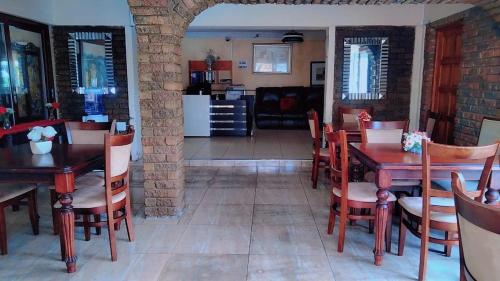 una sala da pranzo con tavoli e sedie e una cucina di Bibby's B&B a East London