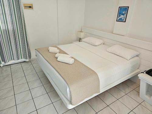 a white bed with two pillows on it in a room at Meltemi Village Hotel in Perissa