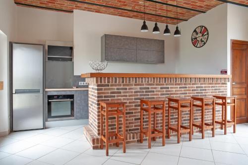 une cuisine avec des tabourets en bois et un mur de briques dans l'établissement Le Cheval Blanc - Proche Amiens grand jardin, à Damery