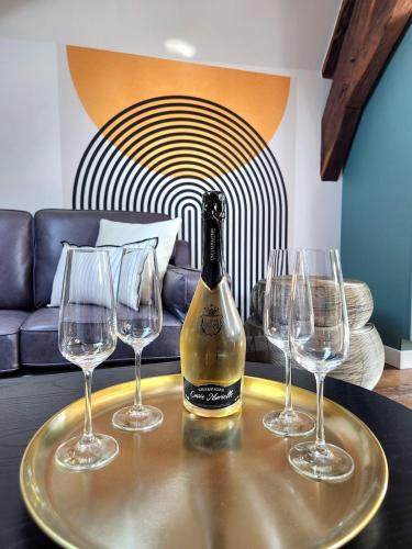 - une bouteille de vin sur une table avec trois verres à vin dans l'établissement Les Bulles d'Aÿ - Loft, à Ay