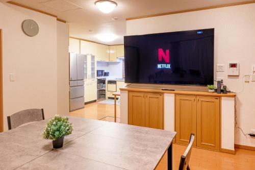 a living room with a table and a flat screen tv at House Villa Kagura in Asahikawa