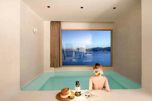 a woman sitting in a bath tub with a window at Shenzhen GuanHu Secret Wild Reef Seaview Hotel in Shenzhen