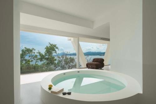 a white room with a tub in front of a window at Shenzhen GuanHu Secret Wild Reef Seaview Hotel in Shenzhen