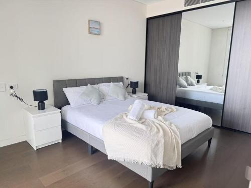 a bedroom with a large bed and a mirror at New Apartment in Olympic Park with Pool and Gym in Sydney
