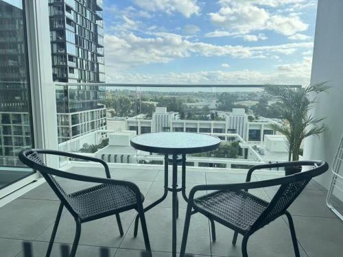 a table and two chairs on a balcony with a view at New Apartment in Olympic Park with Pool and Gym in Sydney