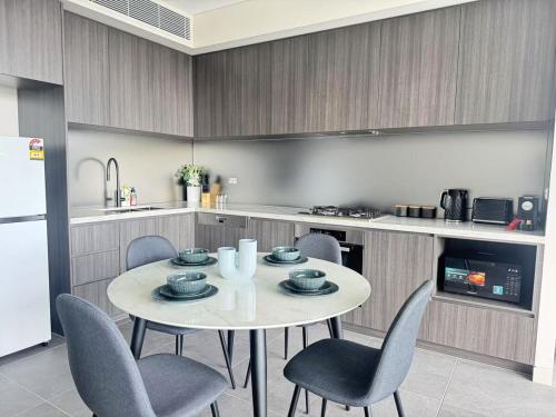 a kitchen with a table and chairs in a kitchen at New Apartment in Olympic Park with Pool and Gym in Sydney