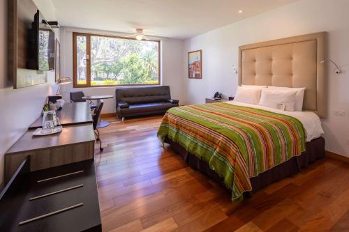 a bedroom with a bed and a desk and a chair at San Jose de Puembo Quito Airport, an Ascend Collection Hotel in Puembo
