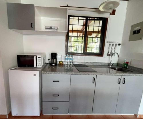 a kitchen with white cabinets and a microwave and a window at San Jose de Puembo Quito Airport, an Ascend Collection Hotel in Puembo