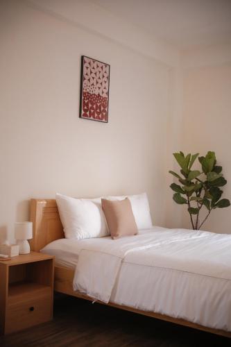 a bedroom with a bed with white sheets and a plant at Glory 2 Hue Homestay in Hue