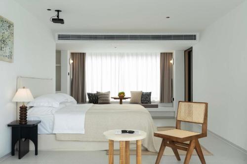 a bedroom with a white bed and a chair at Shenzhen GuanHu Secret Wild Reef Seaview Hotel in Shenzhen